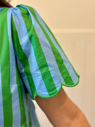 Green and blue striped garment on a person against a neutral background
