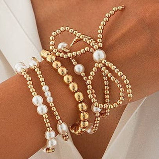 Gold and pearl beaded bracelet on a wrist against a neutral background
