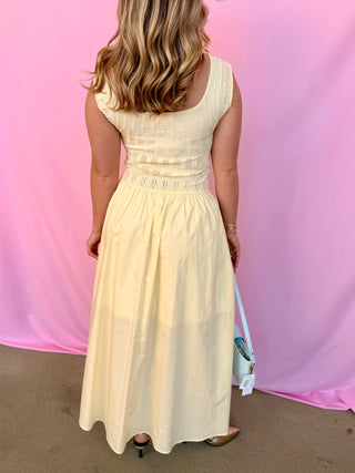 Woman wearing a light yellow dress against a pink and purple gradient background