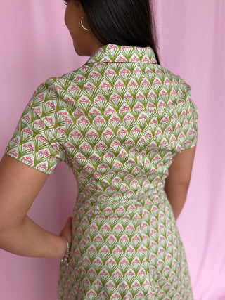 Person wearing a green and pink patterned dress against a pink background
