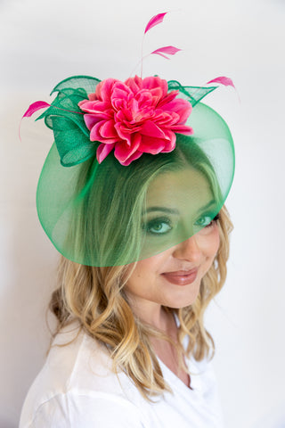 Woman wearing a green and pink floral hat against a white background