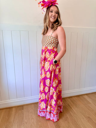 Woman wearing a floral dress and headpiece indoors against a white paneled wall.