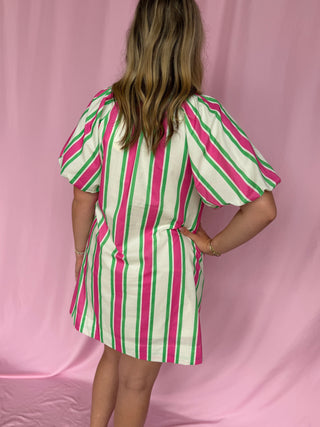 Person wearing a striped dress against a pink background