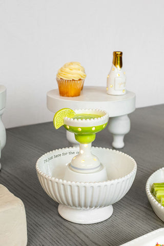 Decorative white pedestal with a green rim holding a lemon wedge, on a gray surface.