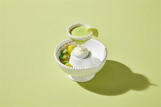 Small white ceramic bowl with colorful candies on a light green background