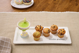 Tray of muffins with a small decorative cup and saucer on a wooden table.