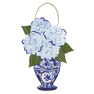 Decorative wall hanging with blue hydrangeas in a vase on a white background