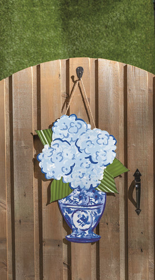 Decorative door hanger with blue floral design on a wooden door.