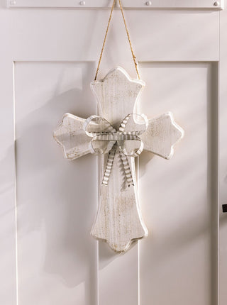 Decorative cross with a bow hanging on a white door