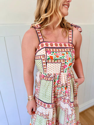 Woman wearing a colorful patterned dress against a white wall.
