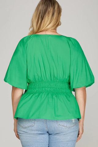 Green blouse worn by a person on a plain background