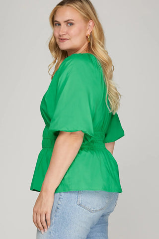 Woman wearing a green blouse with a plain background