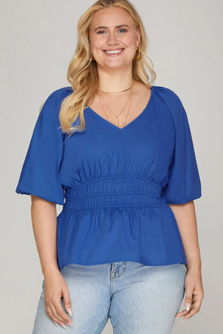 Woman wearing a blue blouse and light blue jeans against a plain background