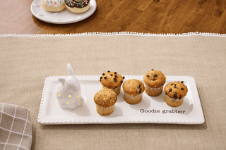 Muffins on a 'Goodie Grabber' tray with a decorative rabbit on a wooden table.