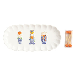 Decorative white pumpkin-shaped platter with autumn-themed design and a set of wooden spoons on a white background.