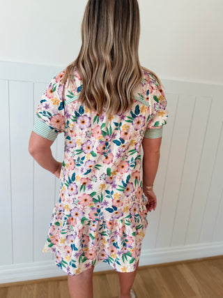 Person wearing a floral dress with a white paneled wall background