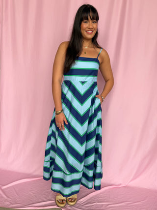 Woman wearing a blue and green striped dress against a pink background