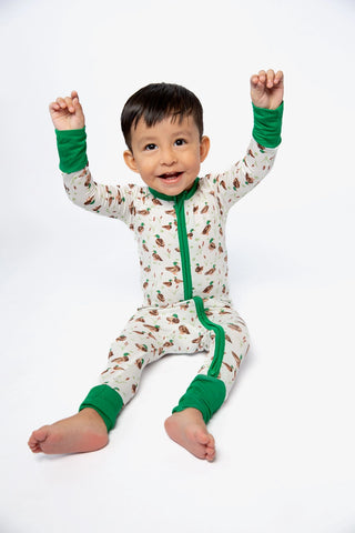 Child wearing a green and white patterned onesie with green accents on a white background