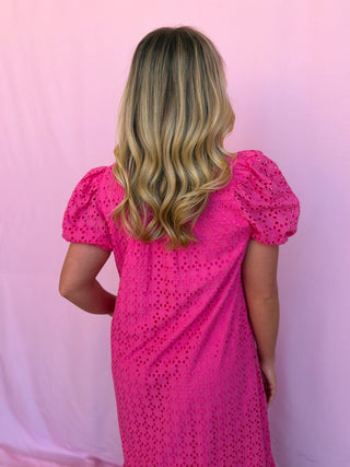 Person wearing a pink dress with puff sleeves against a pink background
