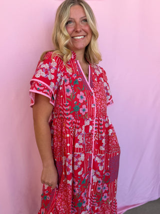 Woman wearing a red floral dress against a pink background