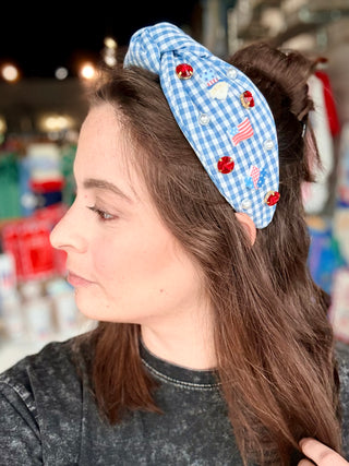 Woman wearing a blue checkered headband with decorative elements in an indoor setting