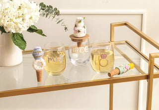 Wine glasses with 'Mrs.' and 'Bride' on a decorative table with flowers and decorative items.