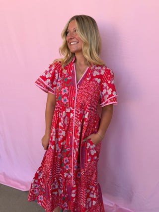 Woman wearing a red floral dress against a pink background