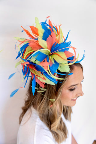 Woman wearing a colorful feathered headpiece against a white background