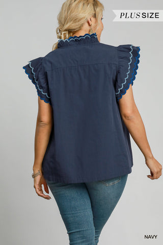 Woman wearing a navy blue blouse with ruffled sleeves on a gray background