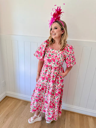 Woman wearing a floral dress and pink headpiece indoors.