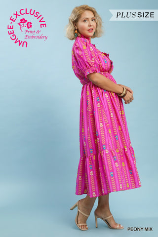 Woman wearing a pink dress with patterns on a light blue background, featuring Umgee Exclusive branding.
