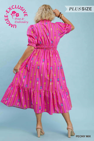 Woman wearing a pink patterned dress on a light blue background with 'UMgee Exclusive' branding.