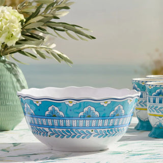 Decorative bowl with blue and white pattern on a table with flowers and another bowl in the background.