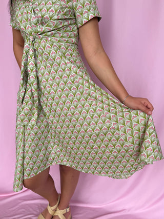 Green and pink patterned dress on a person against a pink background