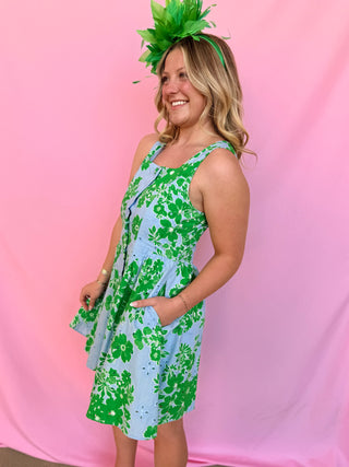 Woman wearing a green floral dress and headband against a pink background