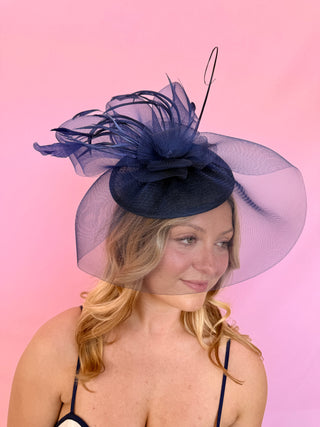 Woman wearing a large decorative hat against a pink background