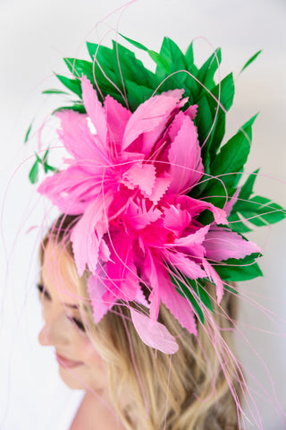 Woman wearing a headpiece with pink feathers and green leaves on a white background
