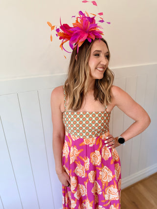 Woman wearing a colorful floral dress and feathered headpiece indoors.
