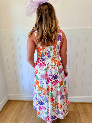 Woman wearing a colorful floral dress with a white wall background