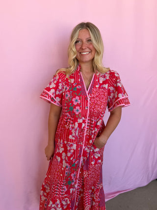 Woman wearing a red floral dress against a pink background