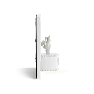 White electronic device with a small figurine on top on a white background