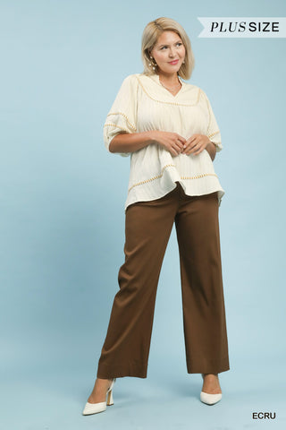 Woman wearing a white blouse and brown pants on a light blue background