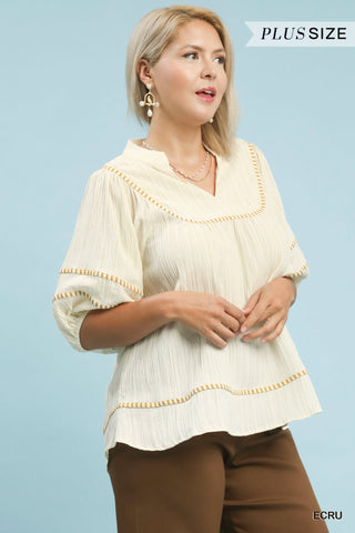 Woman wearing a beige blouse with decorative trim on a light blue background