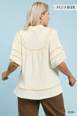 Woman wearing a beige blouse with decorative trim on a light blue background