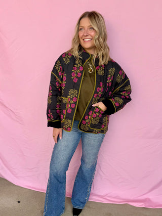 Woman wearing a floral embroidered jacket against a pink background