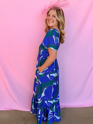 Woman wearing a blue floral dress against a pink background