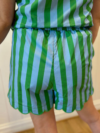 Green and blue striped outfit worn by a person against a white wall.