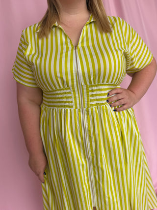 Person wearing a yellow and white striped dress against a pink background