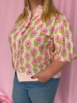 Person wearing a floral blouse with a pink background