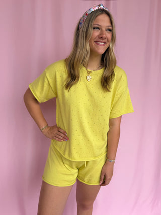 Woman wearing a yellow outfit with a floral headband against a pink background